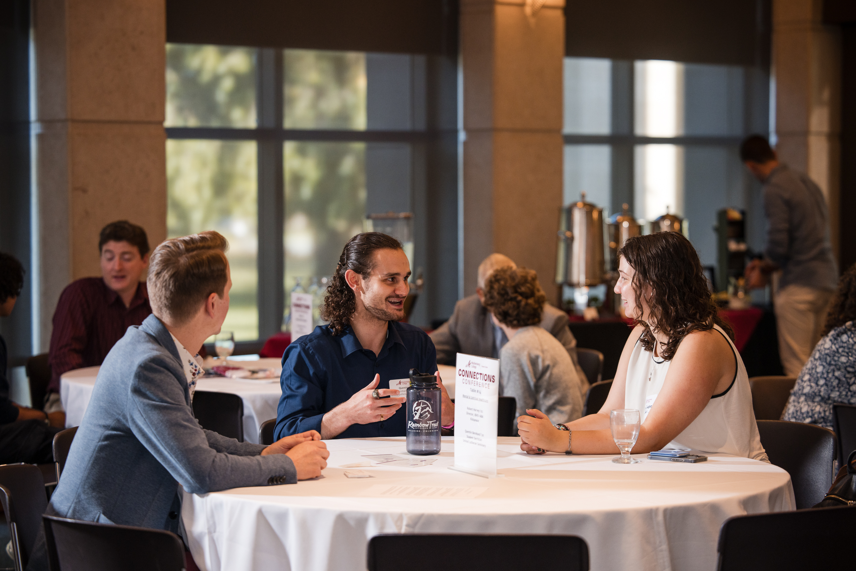 A two men talk to college students during a roundtable networking event